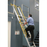 Person using a mezzalad ladder with yellow handrails against a gray warehouse wall.