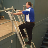 Man on a mezzalad ladder working on a platform against a gray wall.